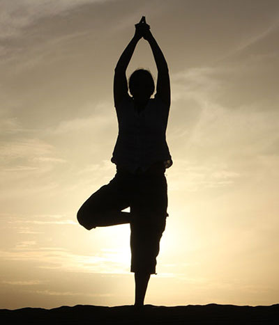 Yogaübung "Der Baum" in den Dünen der Sahara